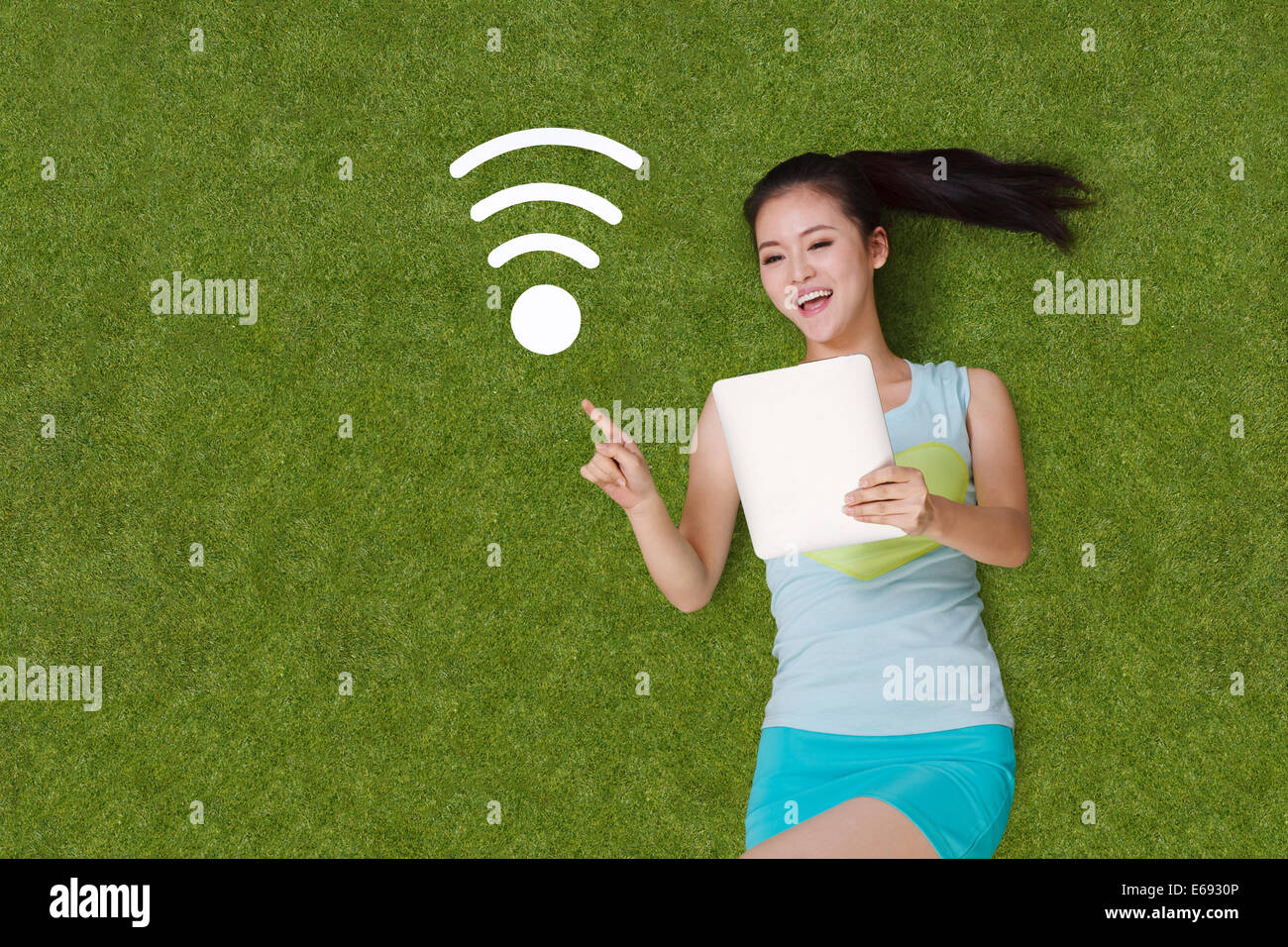 Young woman lying on grass with tablet Stock Photo - Alamy