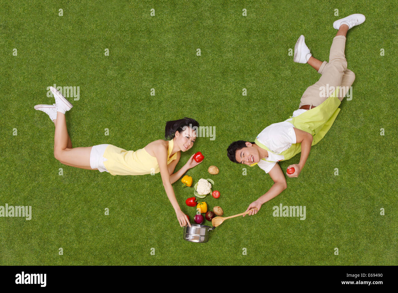 Young couple lying on grass with vegetables Stock Photo - Alamy