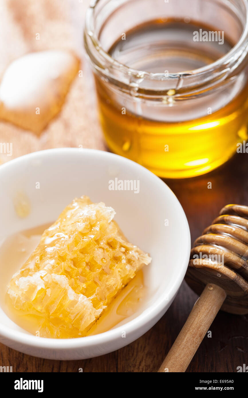 honey comb dripping from dipper into jar with nuts on old wooden table.  Healthy eat Stock Photo by lyulkamazur