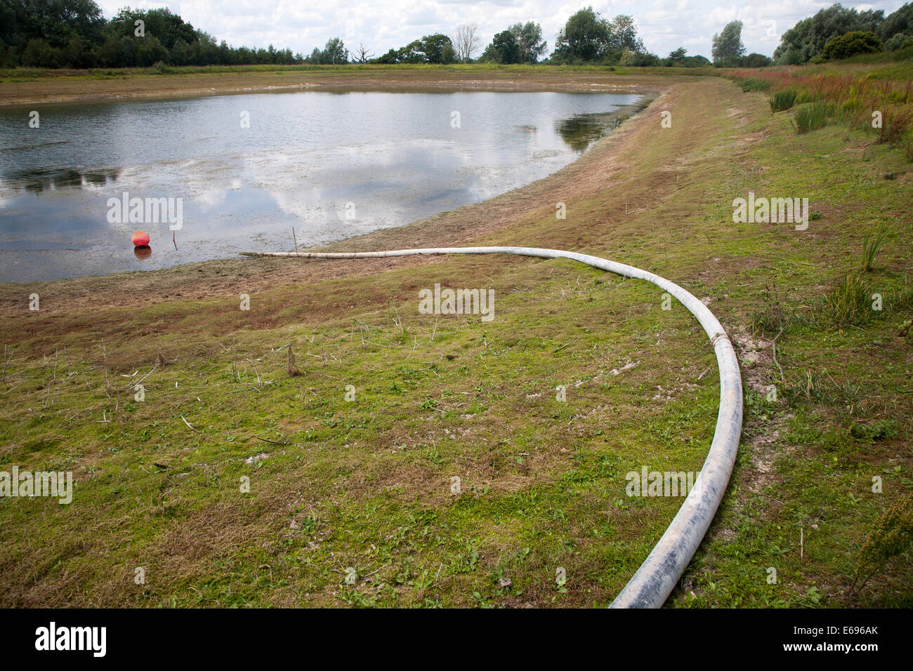 Irrigation pipe water reservoir lake at low level in summer Sutton,  Suffolk, England Stock Photo