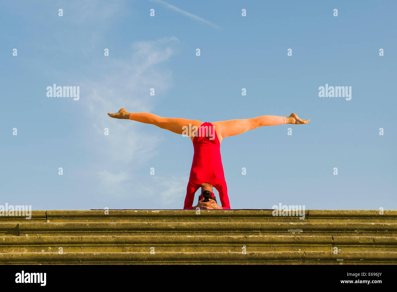 Young woman practising Hatha yoga, outdoors, showing the pose Sirshasana, Head stand Stock Photo