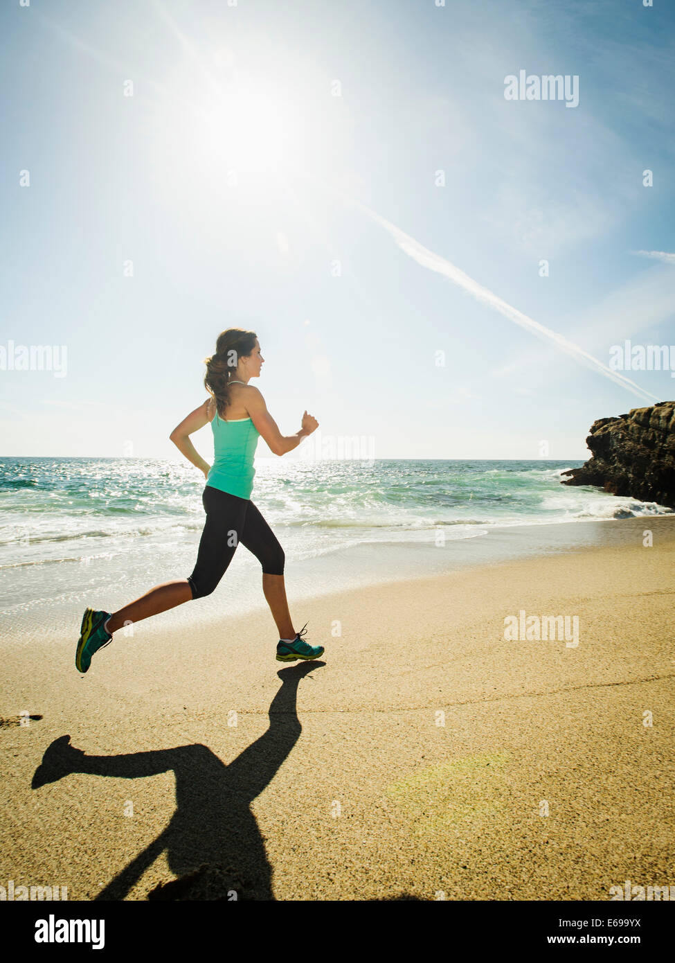 Caucasian woman running on beach Stock Photo
