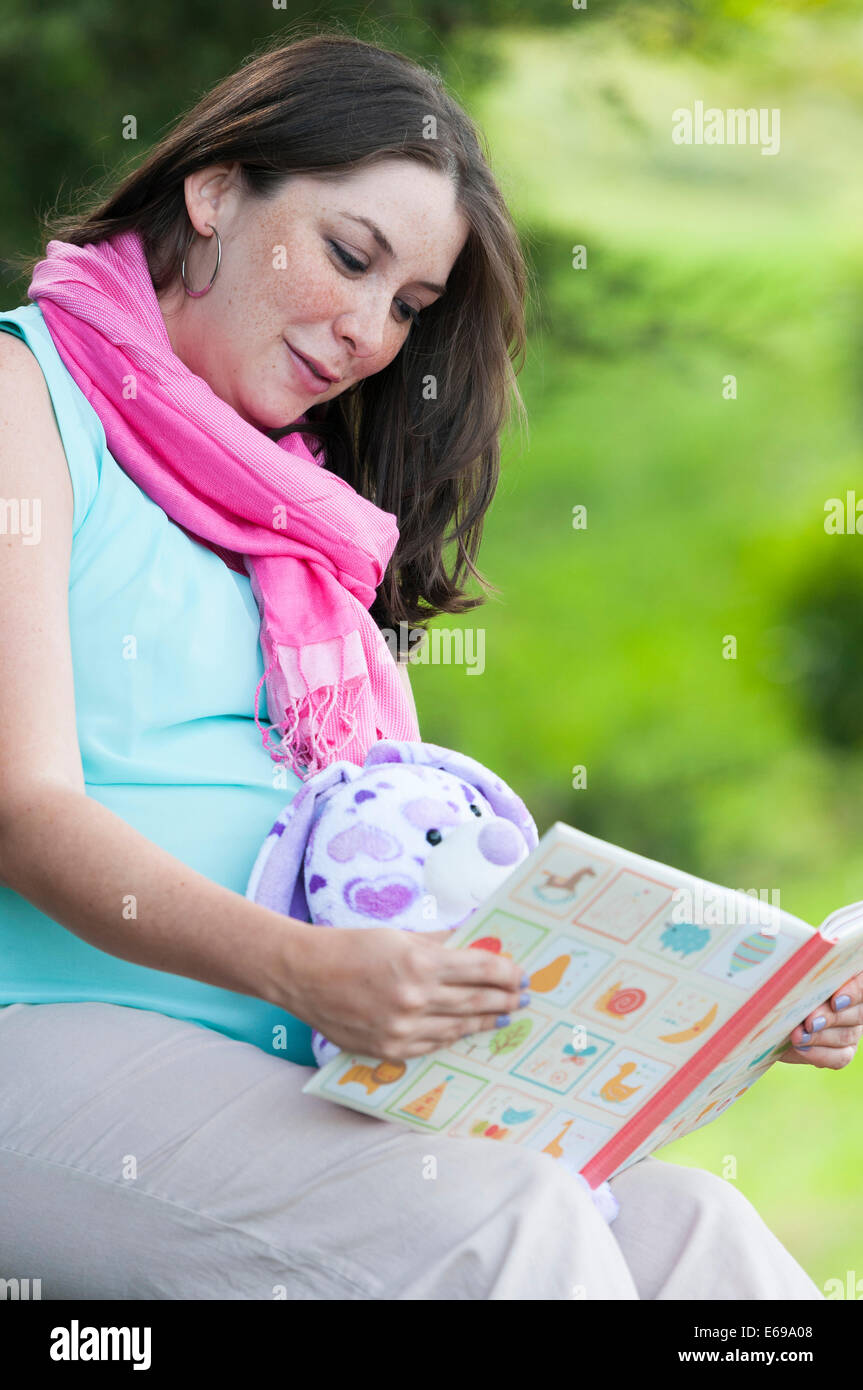Pregnant Hispanic woman reading children's book Stock Photo
