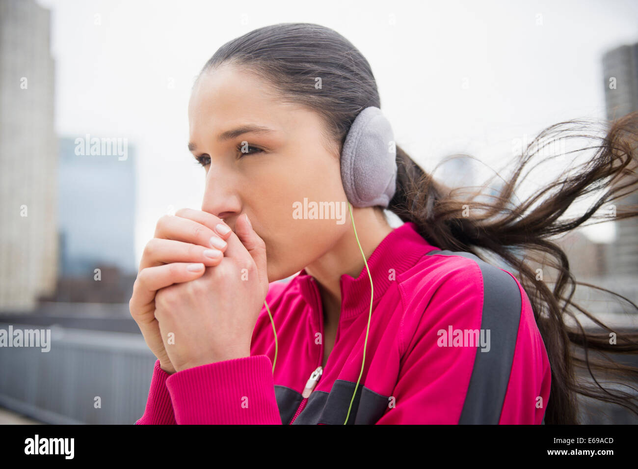Caucasian woman warming hands in city Stock Photo