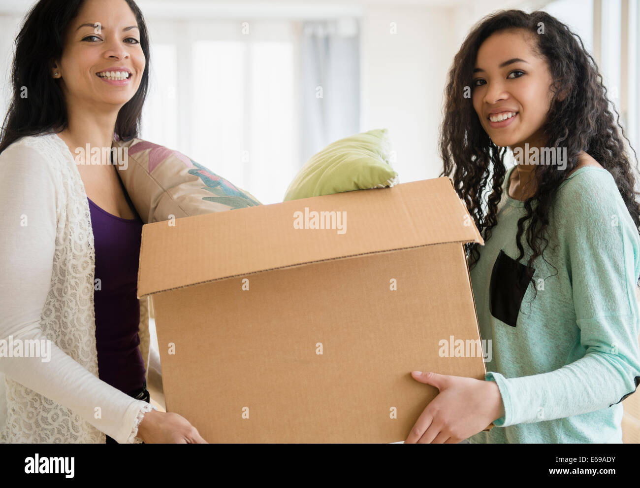 Mother and daughter carrying cardboard box Stock Photo