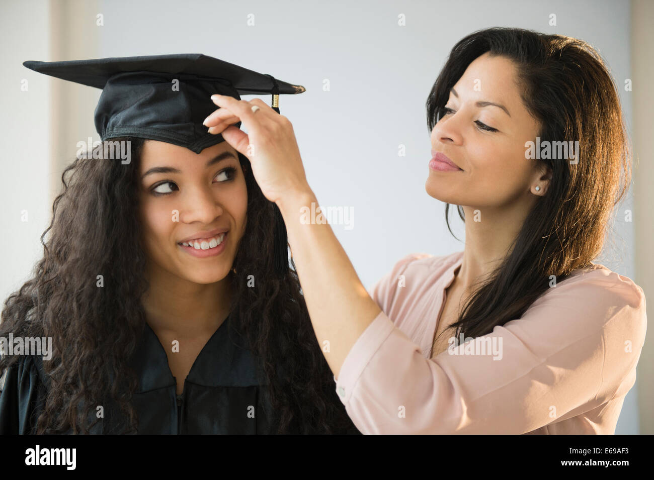 Mother adjusting teenage daughter's graduation cap Stock Photo