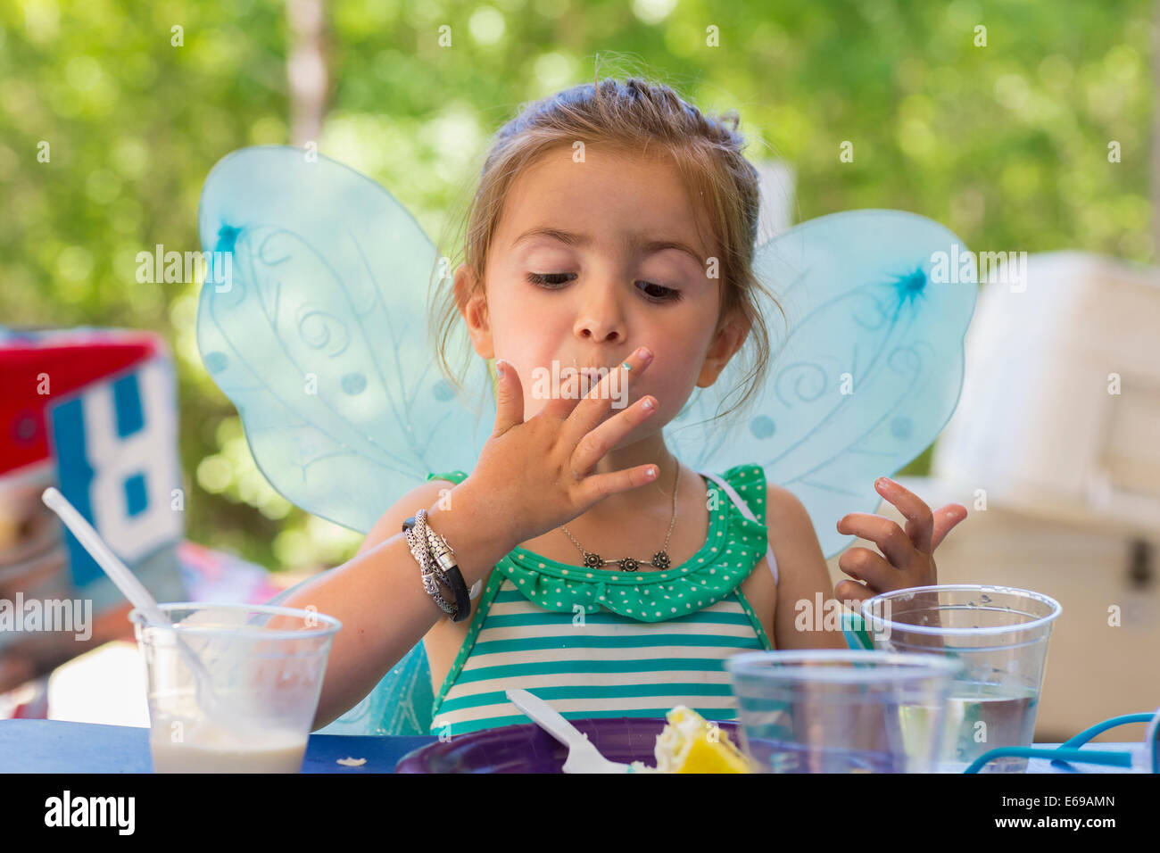 Caucasian girl eating cake at birthday party Stock Photo