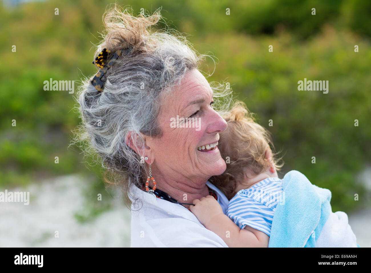 Caucasian woman carrying grandson on beach Stock Photo