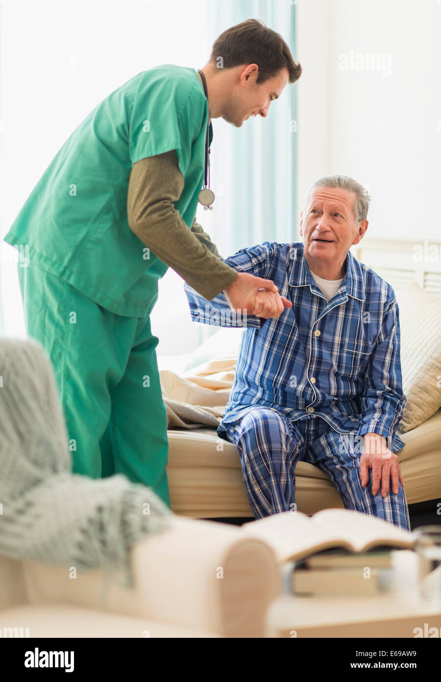 Caucasian nurse helping patient out of bed in home Stock Photo Alamy