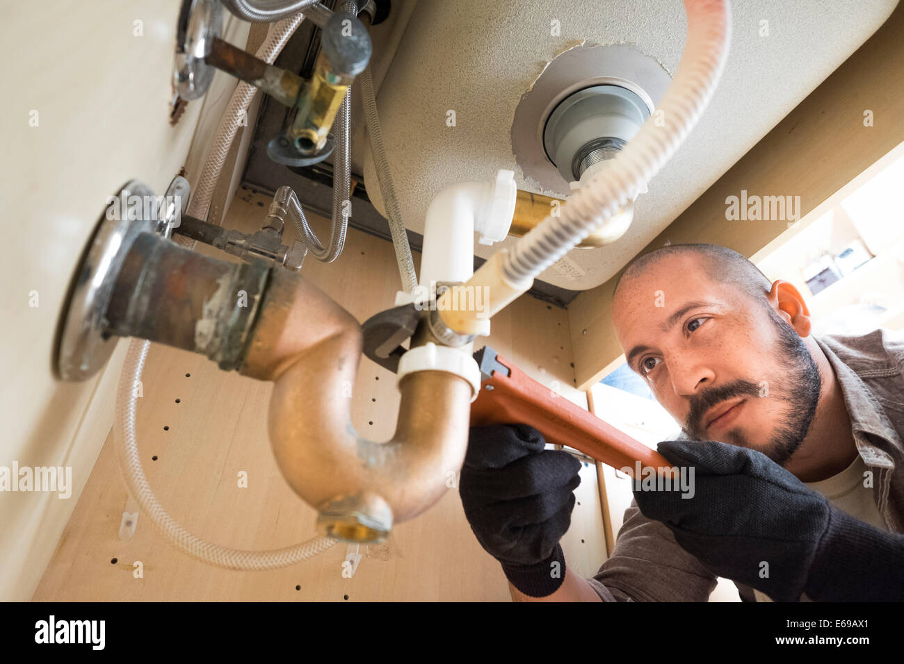 Hispanic plumber working under sink Stock Photo
