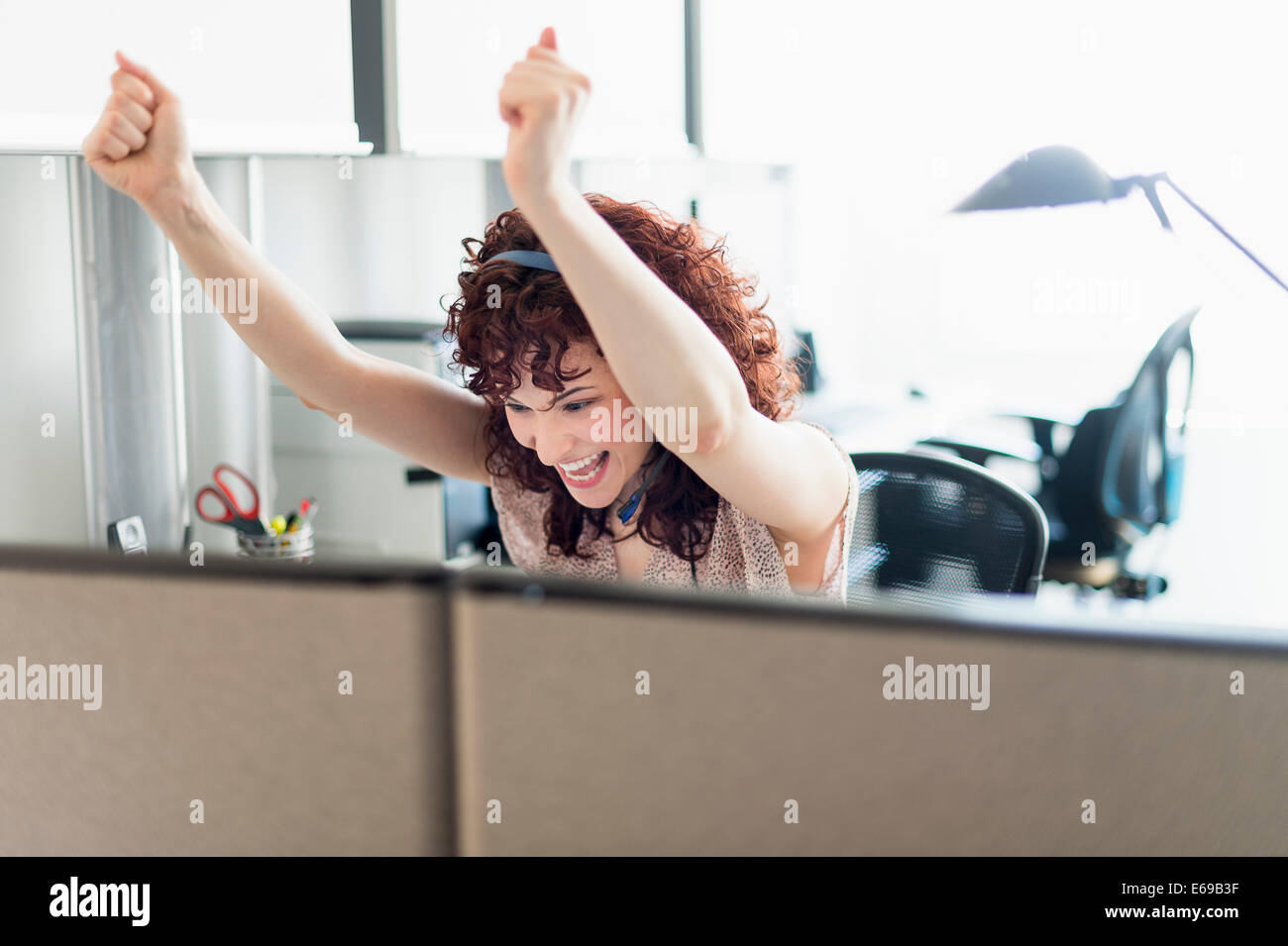 Hispanic businesswoman cheering in office Stock Photo
