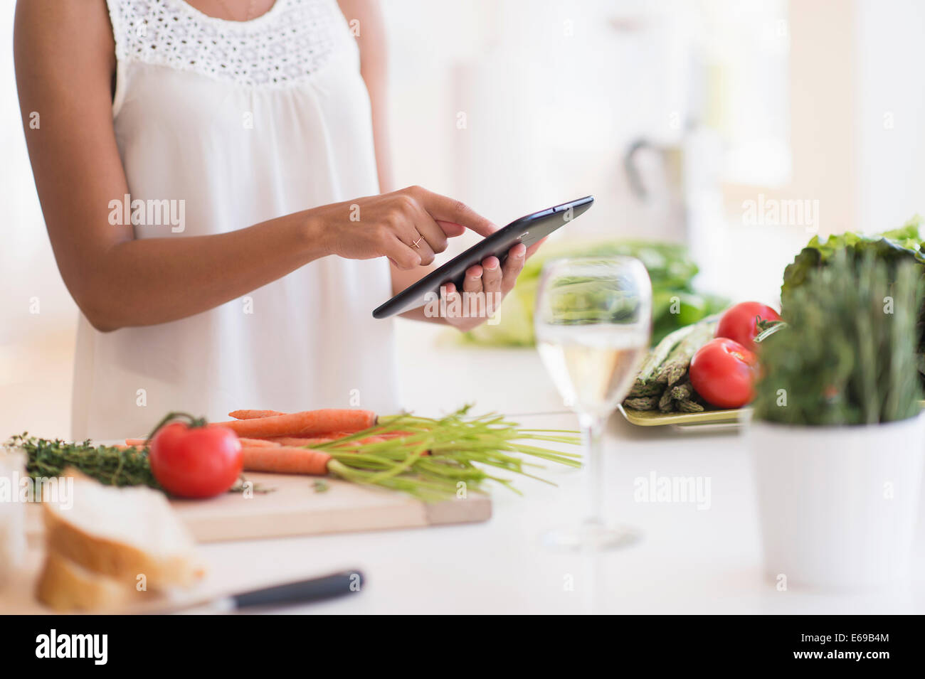 Hispanic woman cooking with digital tablet in kitchen Stock Photo