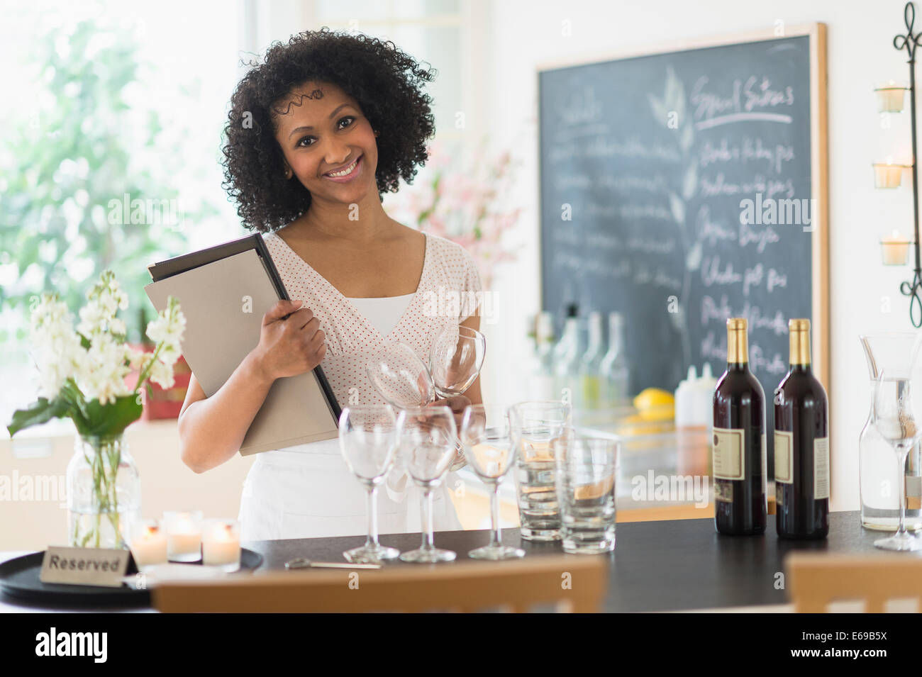 Mixed race hostess smiling in restaurant Stock Photo