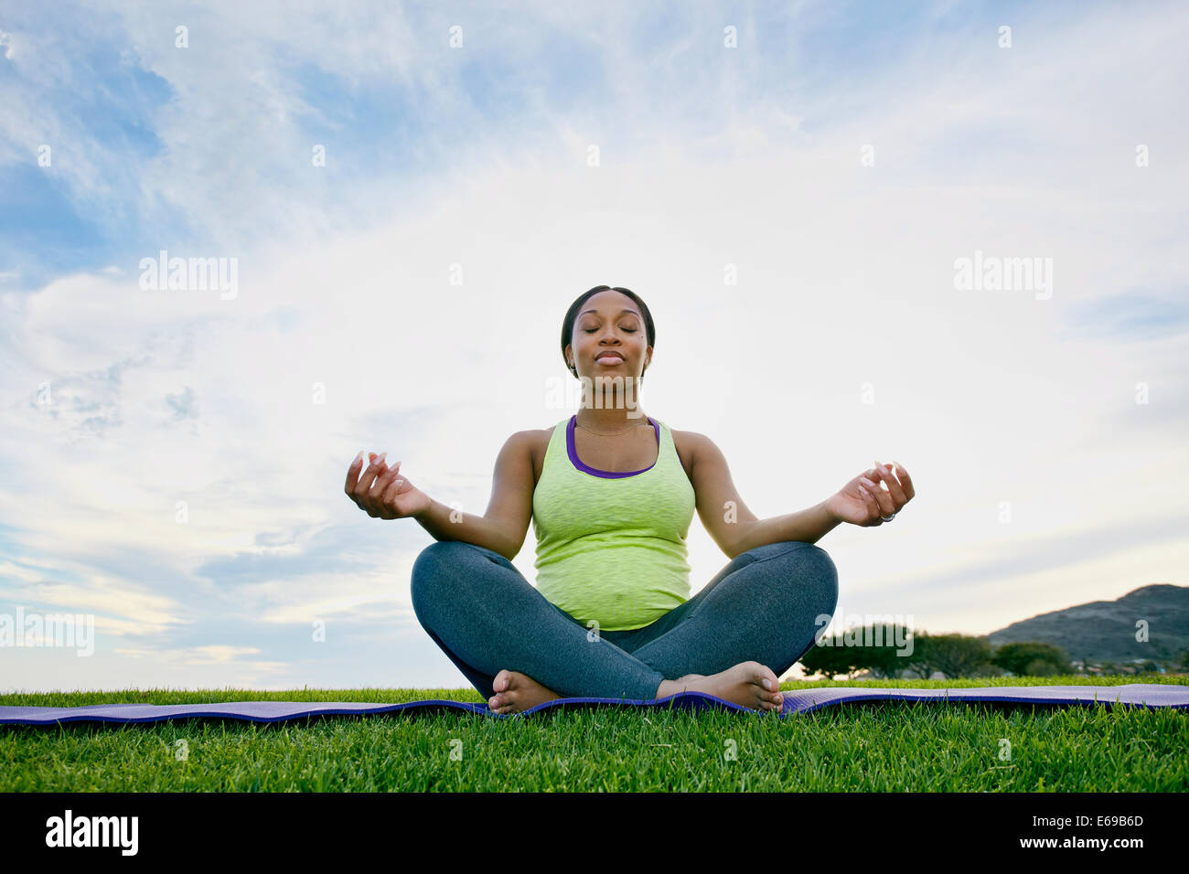 Pregnant woman meditating in park Stock Photo