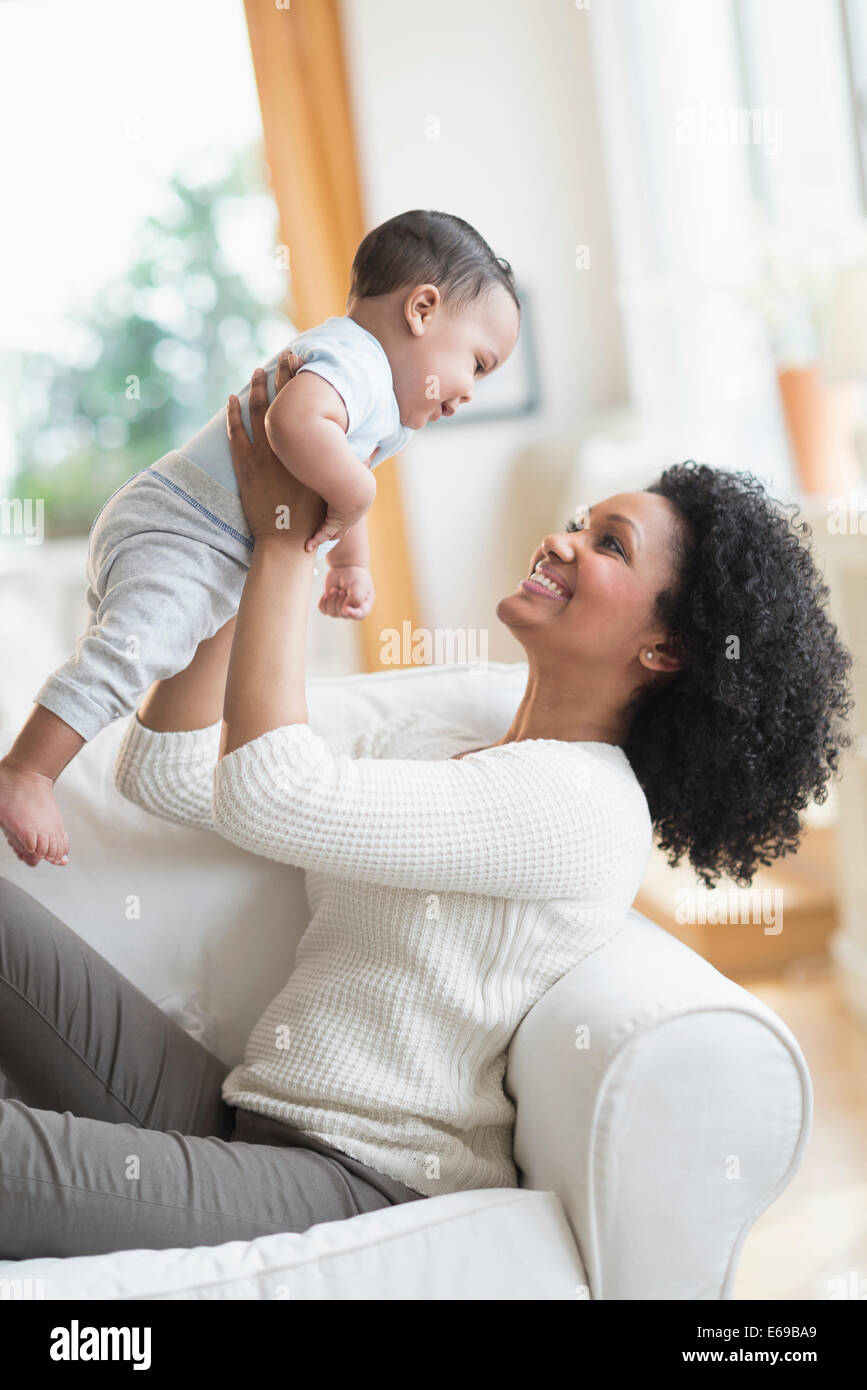Mixed race mother playing with baby on sofa Stock Photo