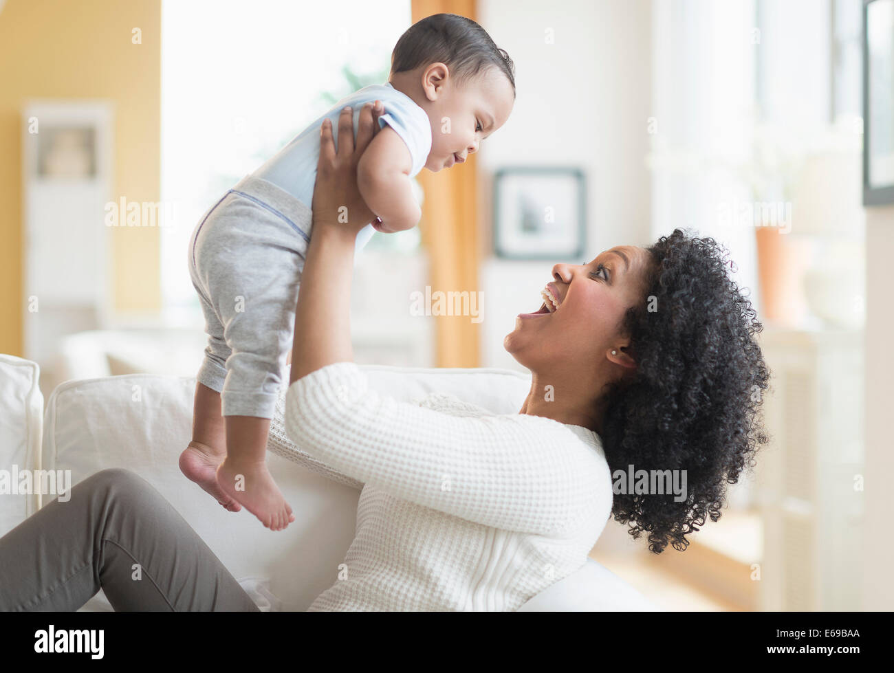Mixed race mother playing with baby on sofa Stock Photo
