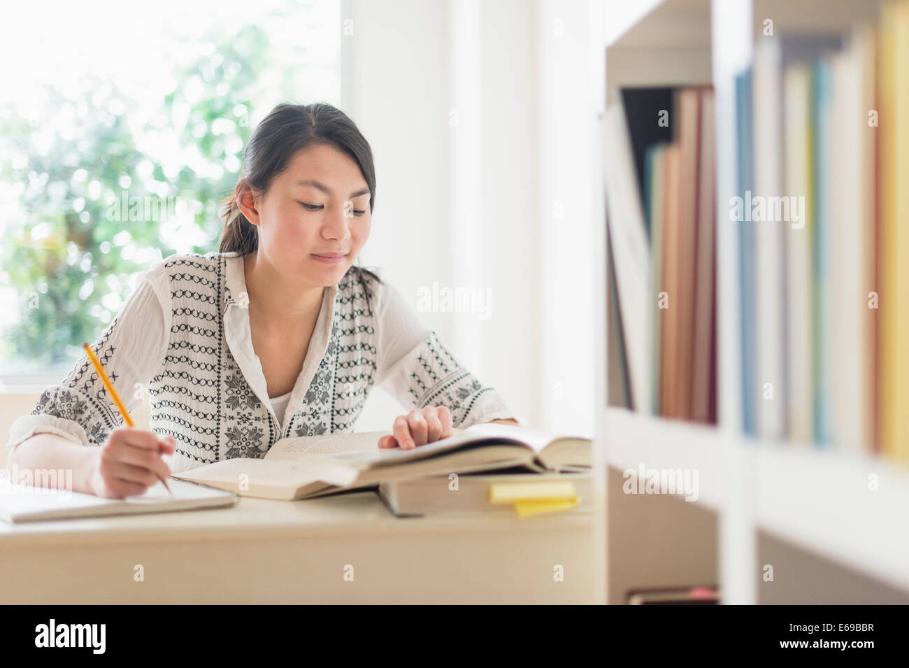 Mixed race teenage girl studying in library Stock Photo
