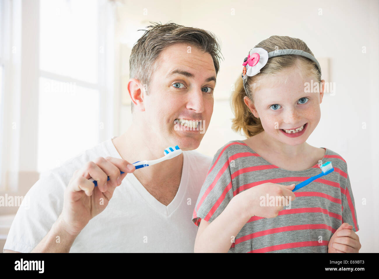 Caucasian father and daughter brushing their teeth Stock Photo