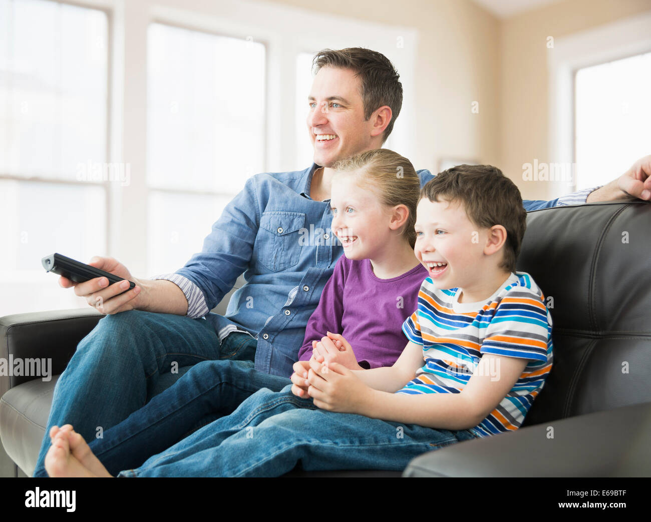 Caucasian father and children watching television on sofa Stock Photo