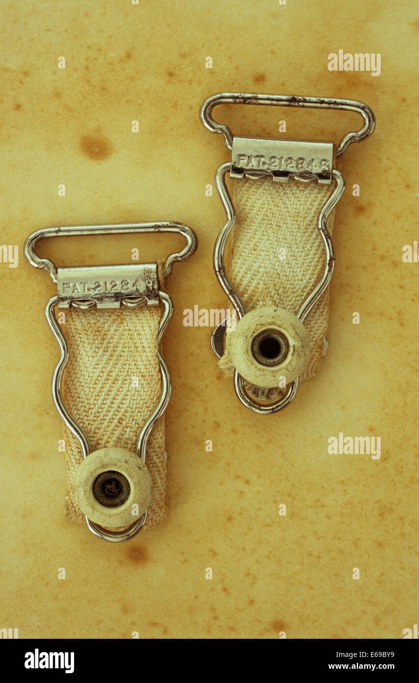 Two white vintage clips from womans stockings suspender belt or girdle  lying on antique paper Stock Photo - Alamy