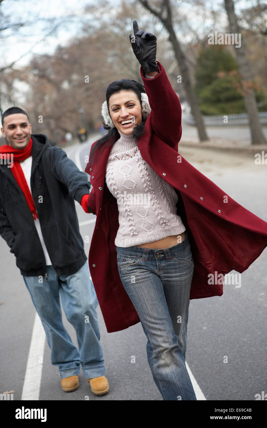 Couple hailing taxi in urban park Stock Photo