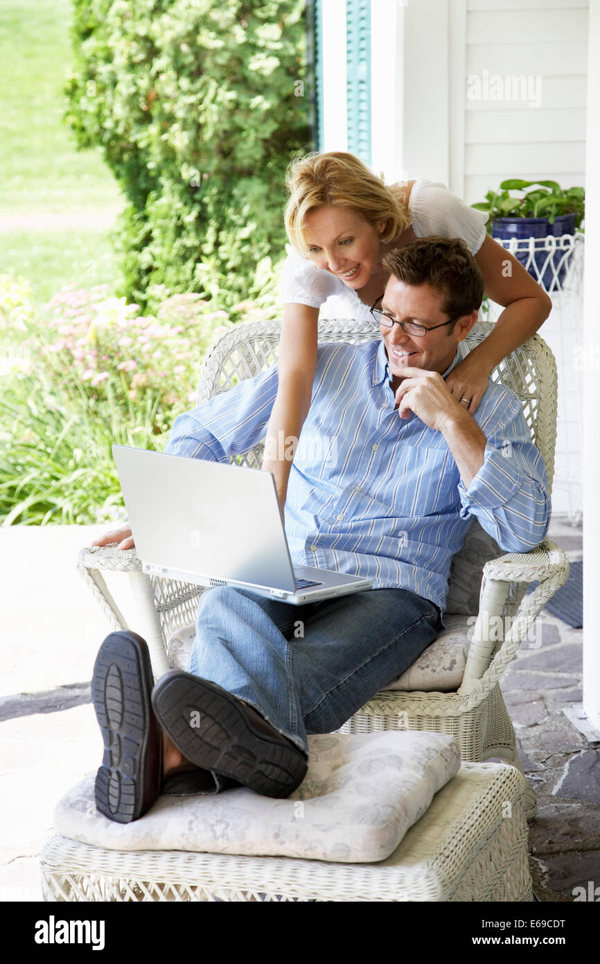Couple using laptop together on patio Stock Photo - Alamy