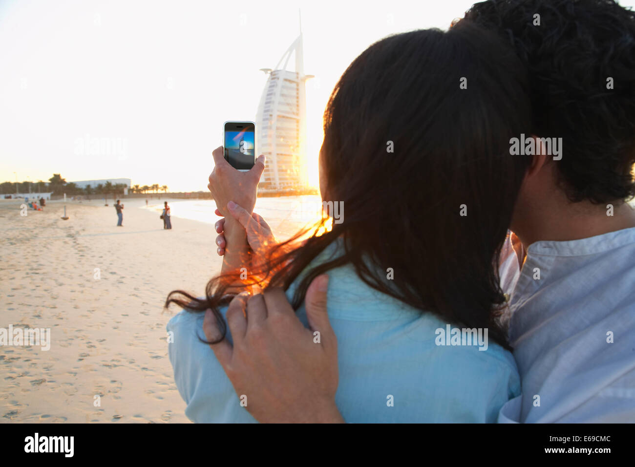 Couple taking pictures together on beach, Dubai, United Arab Emirates Stock Photo