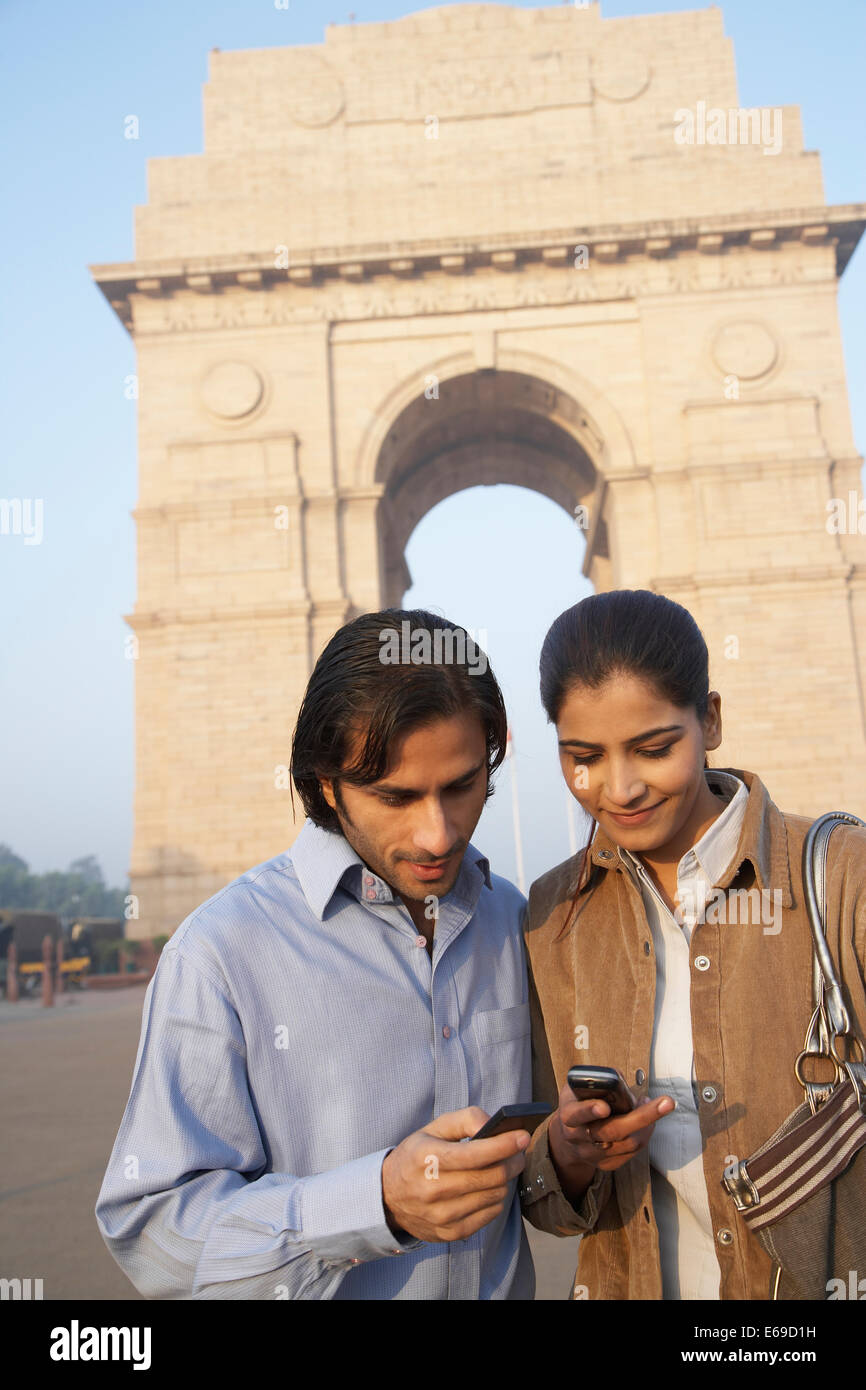 Indian couple using cell phone by India Gate, Delhi, India Stock Photo