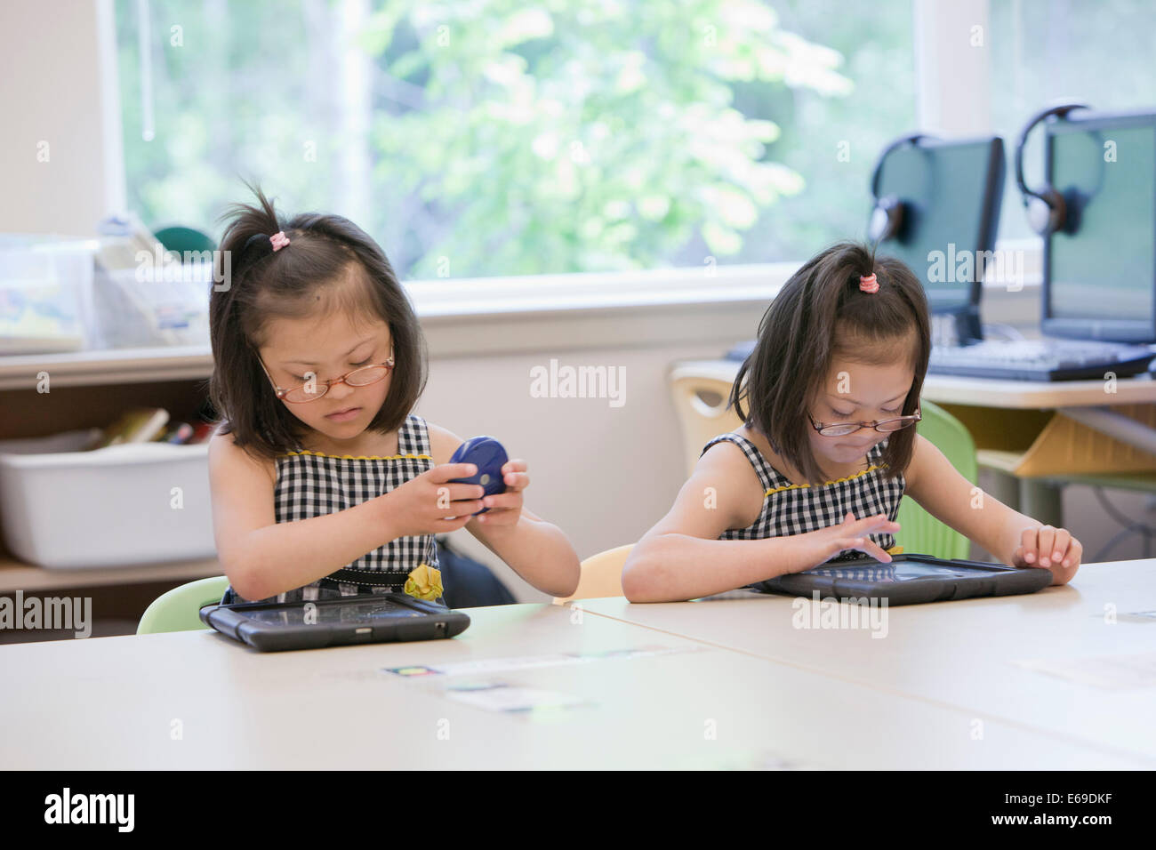 Mixed race Down syndrome students using tablet computers in classroom