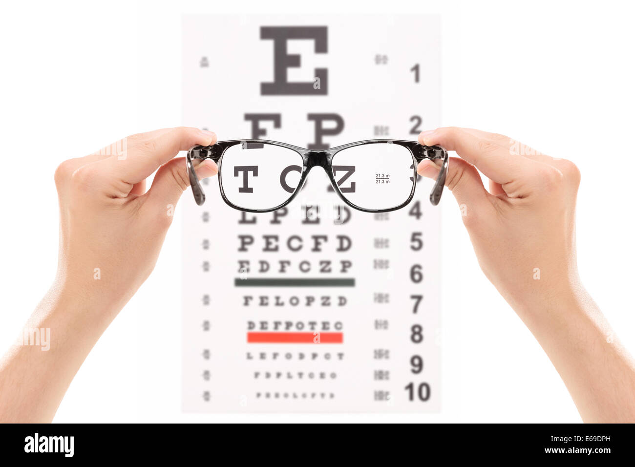Hands holding glasses in front of an eye chart Stock Photo