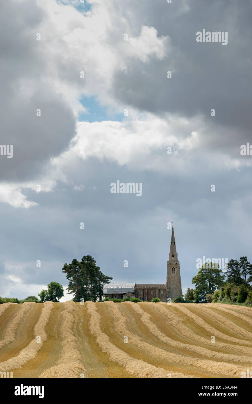 Little Staughton, Bedfordshire, UK. 19th August 2014. Dark clouds gather over the church and newly harvested wheat fields at Little Staughton in north Bedfordshire. Day time temperatures across much of the UK failed to reach 20 degrees C for the first time since early June. Sunshine and showers and a noticeable chill in the air gave a distinctive autumnal feel to the weather. Credit:  Julian Eales/Alamy Live News Stock Photo