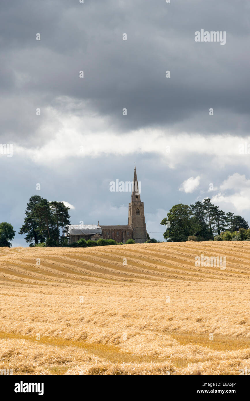 Little Staughton, Bedfordshire, UK. 19th August 2014. Dark clouds gather over the church and newly harvested wheat fields at Little Staughton in north Bedfordshire. Day time temperatures across much of the UK failed to reach 20 degrees C for the first time since early June. Sunshine and showers and a noticeable chill in the air gave a distinctive autumnal feel to the weather. Credit:  Julian Eales/Alamy Live News Stock Photo