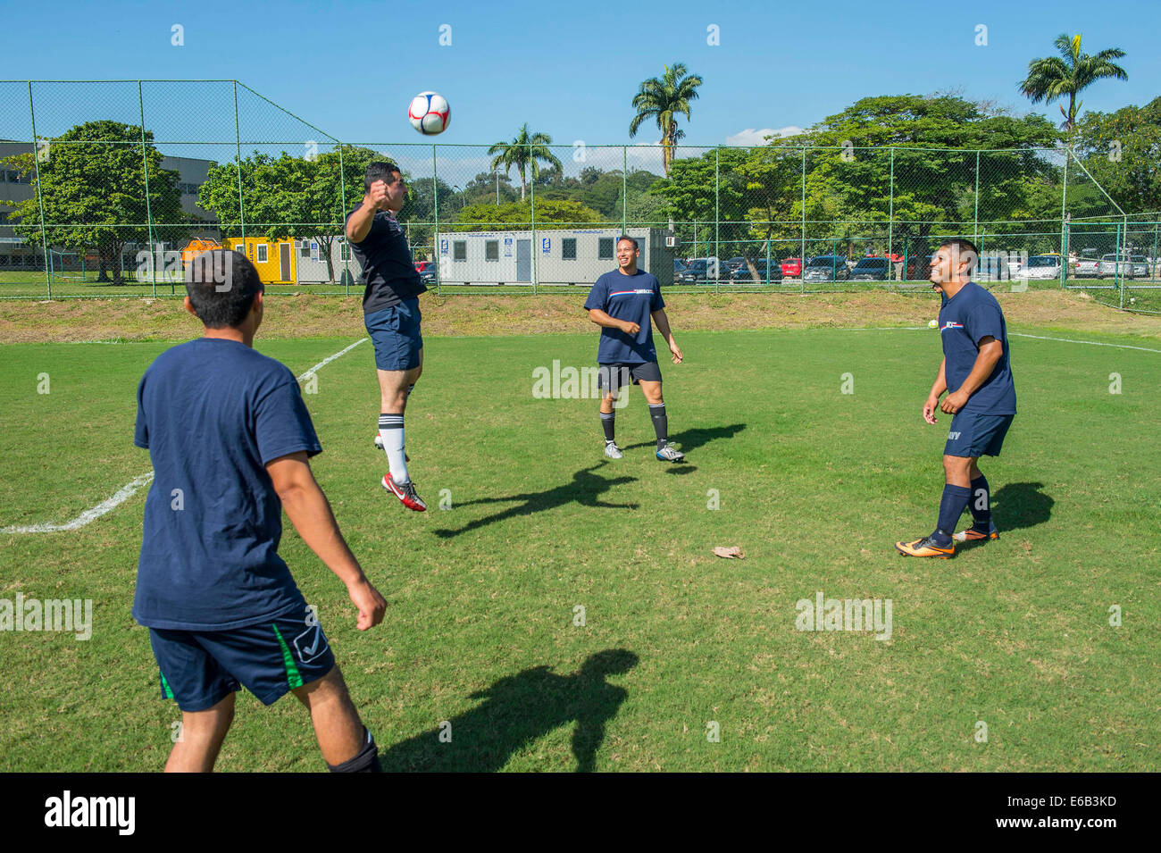U.S. Navy Master-at-Arms 2nd Class Ivan Pellecer, center left, assigned to the newly commissioned amphibious assault ship USS America (LHA 6), bounces a soccer ball off his head as he warms up with teammates before a match against Brazilian sailors Aug. 6 Stock Photo