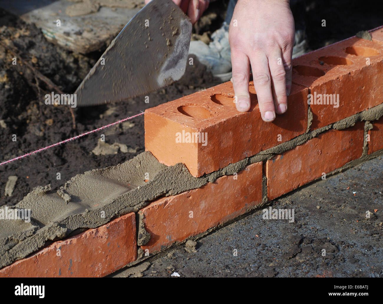 Construction worker laying bricks showing trowel and guideline. Stock Photo
