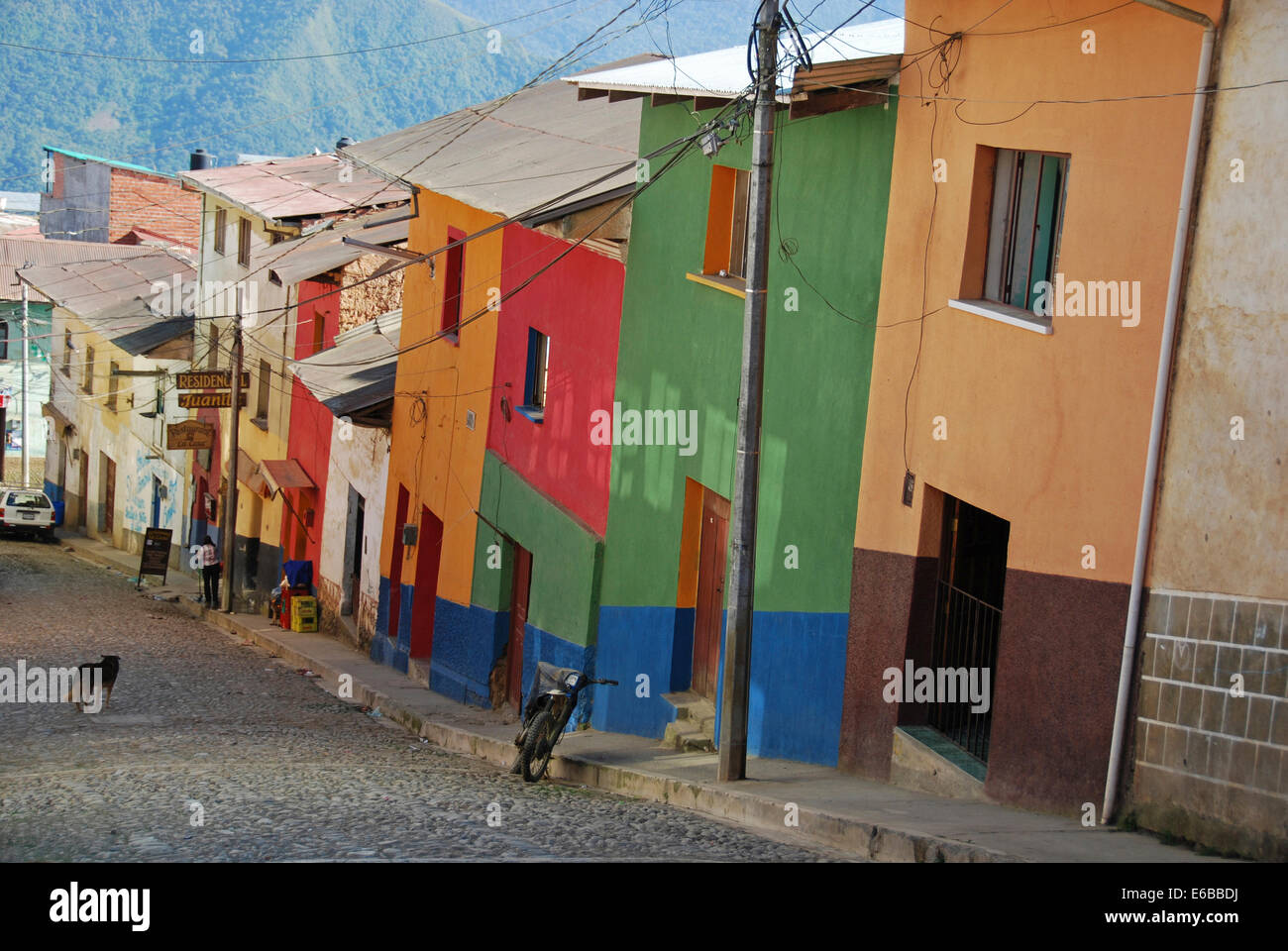 Bolivia, Coroico, motorbike parked on alley by buildings with windows in a row with colorful walls. Stock Photo