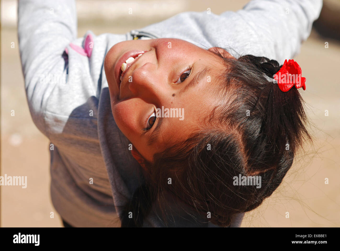 Bolivia, El alto, portrait of a cute smiling girl with plaited hair upside down. Stock Photo