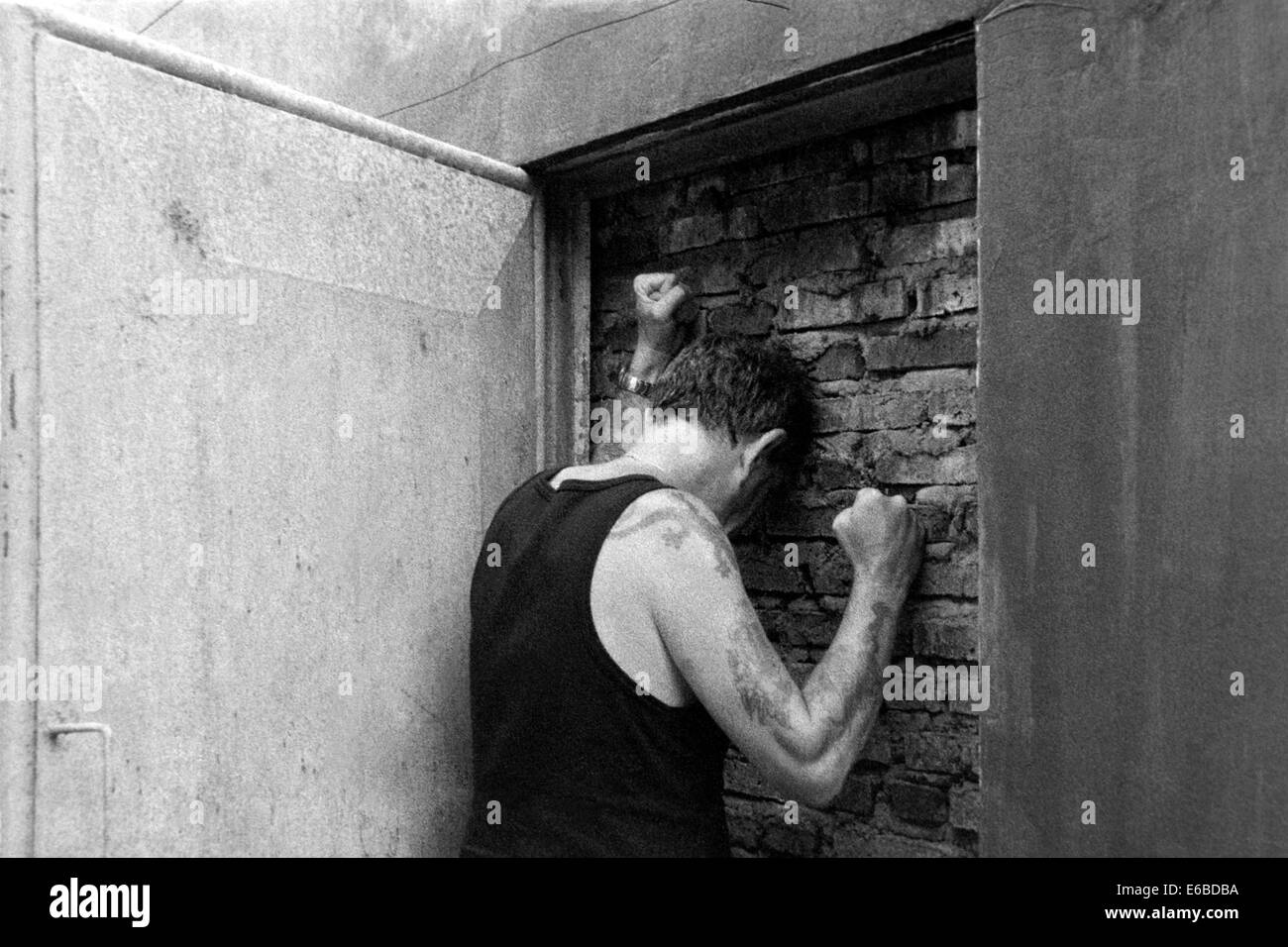 man in open doorway banging fists against a brick wall that is