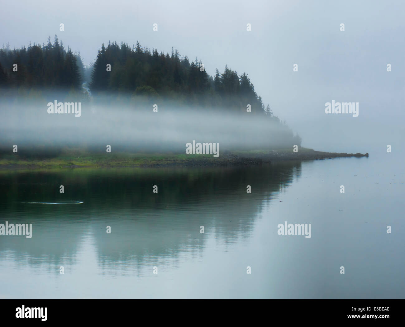 Fog engulfing an island in Southeast Alaska with reflections in the water. Stock Photo