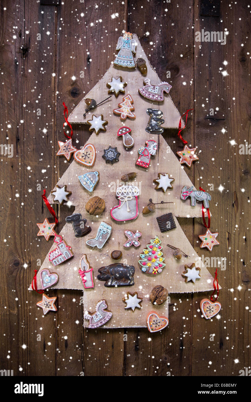 Handmade carved christmas tree decorated with gingerbread, stars and hearts on wooden background. Stock Photo