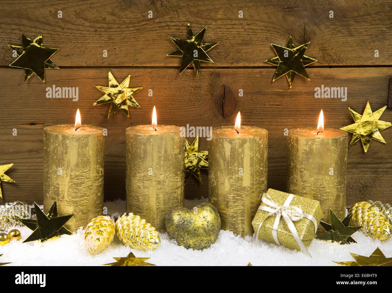 Four golden burning christmas candles for advent decoration on wooden background. Stock Photo