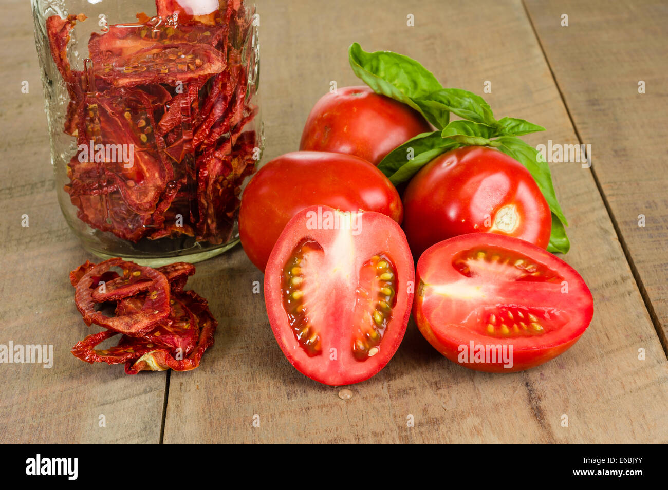 Fresh red tomatoes and basil with jar of dried tomatoes Stock Photo