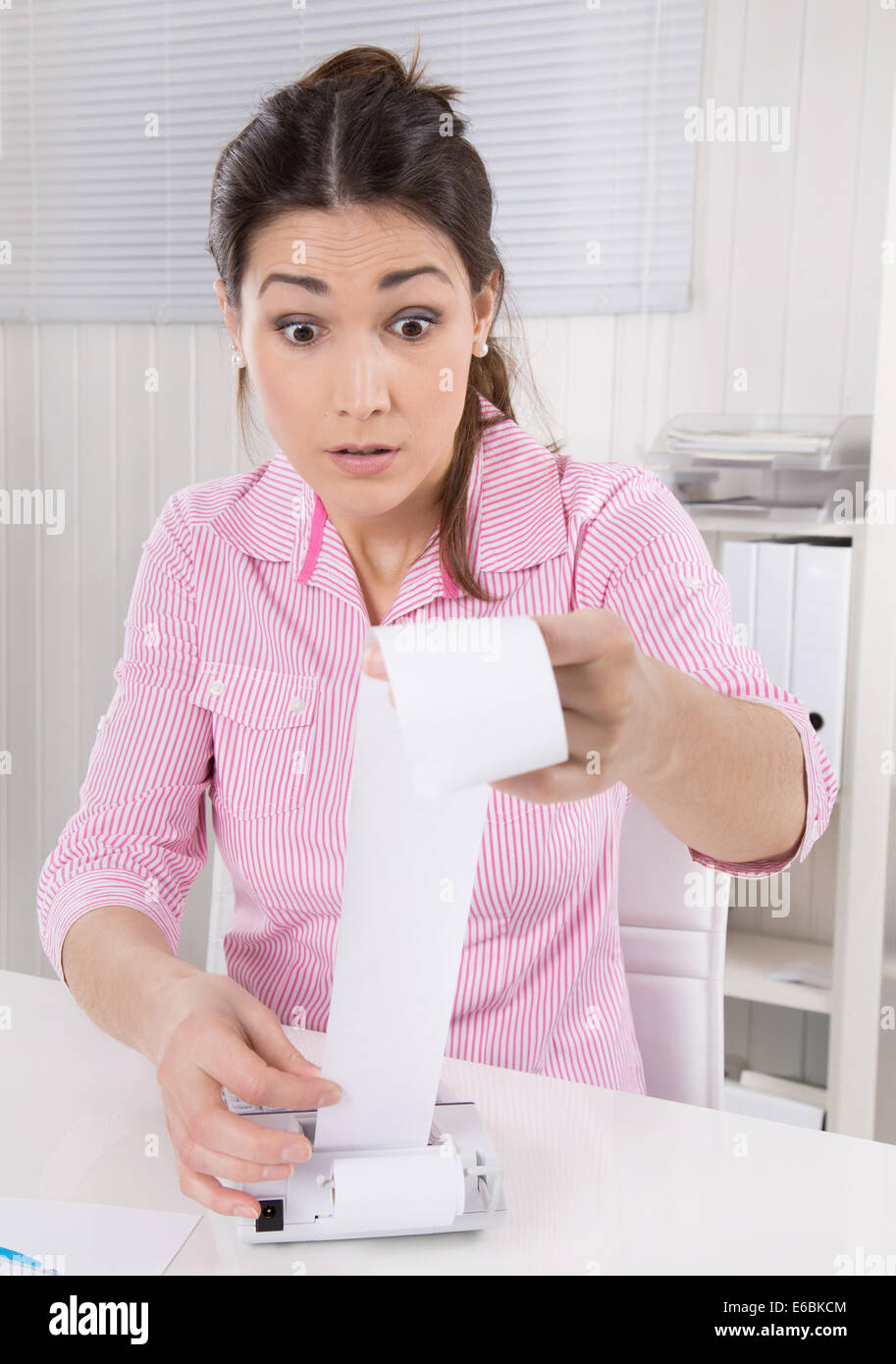 Shocked business woman looking at increasing costs in her company wearing pink blouse. Stock Photo