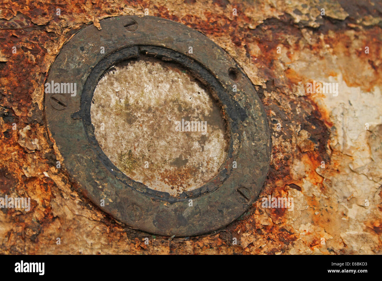 Abstract of textured rusty porthole window on a small boat showing detail of corrosion and oxidization Stock Photo