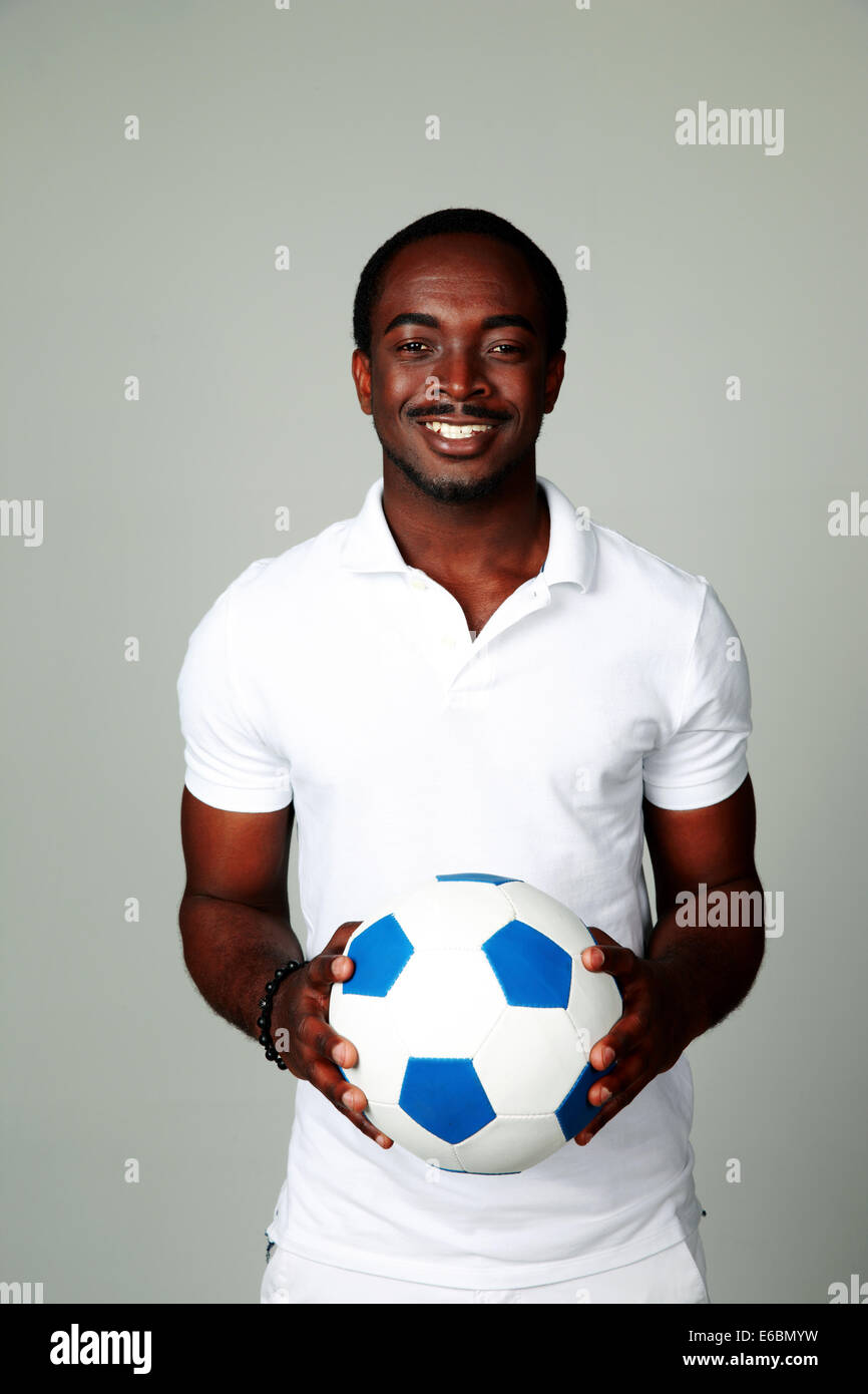 Happy african man holding soccer ball on gray background Stock Photo ...