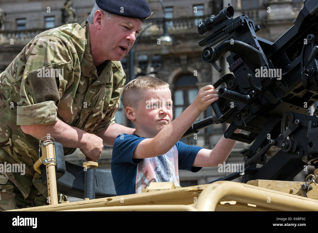 Young boy being given instruction on how to use a machine gun during a military display and parade, George Square, Glasgow, Stock Photo