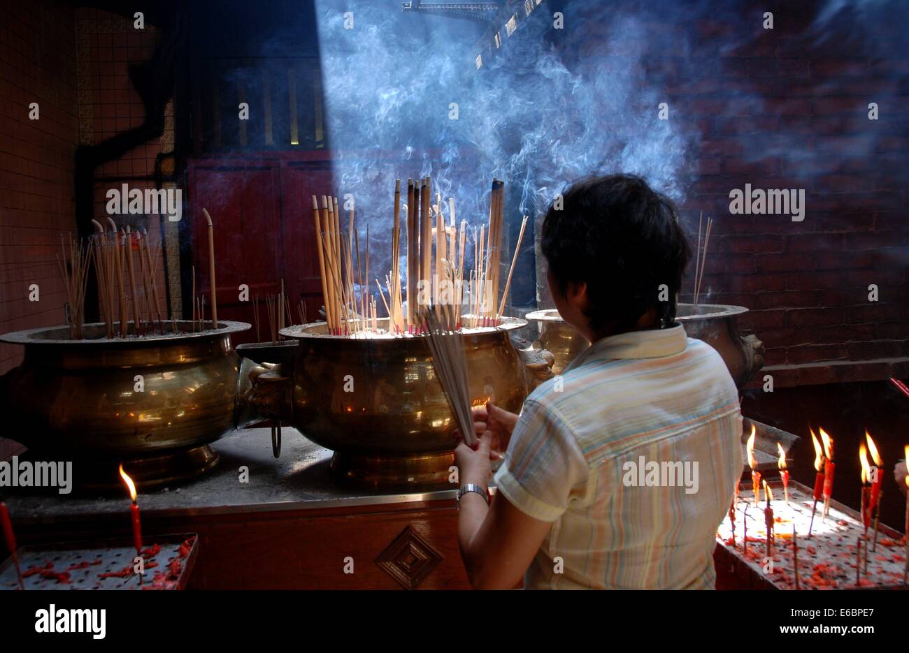 KUALA LUMPUR, MALAYSIA A woman lighting incense sticks at the Sin Sze