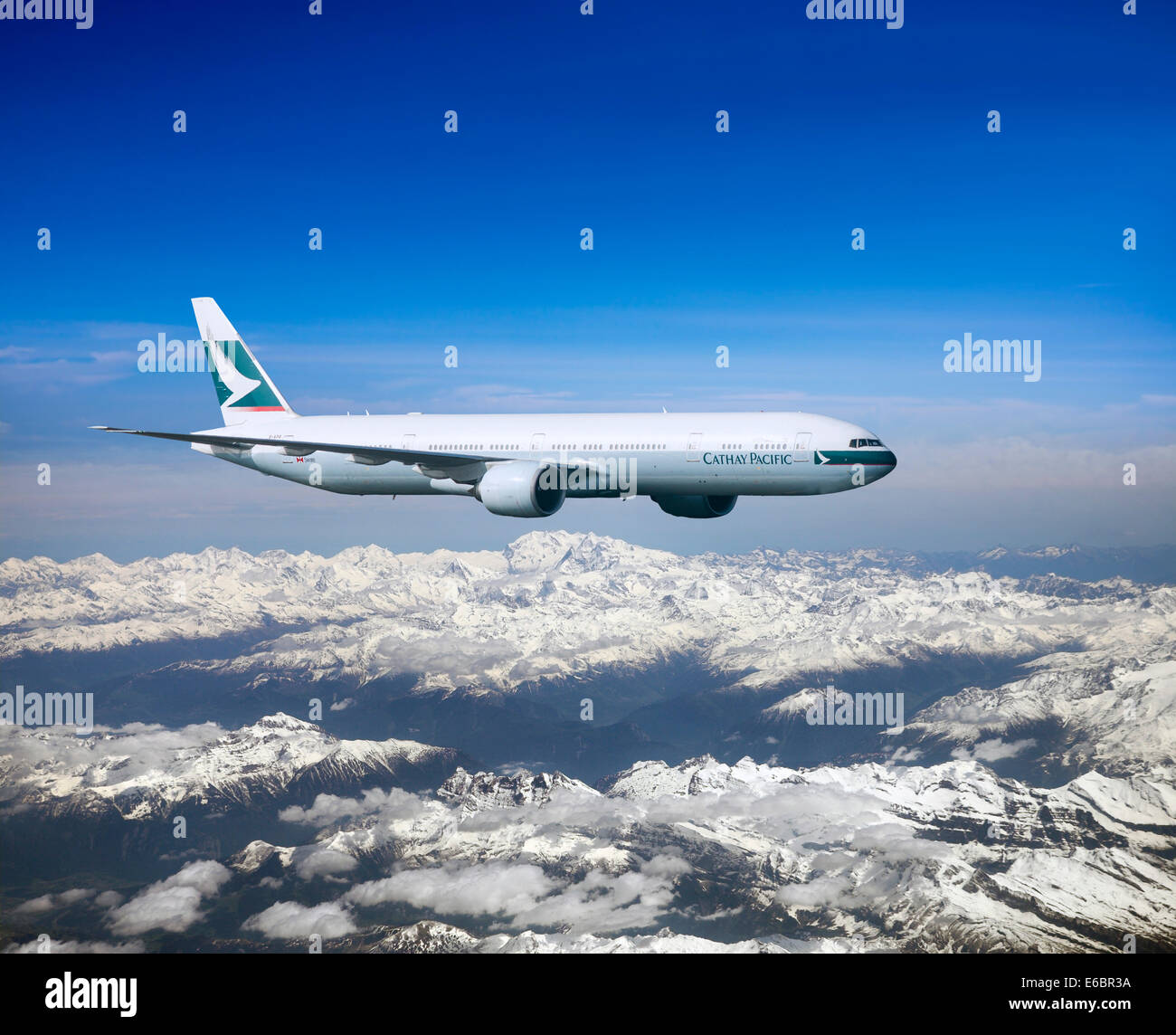 Cathay Pacific Boeing 777-367 ER in flight over mountains Stock