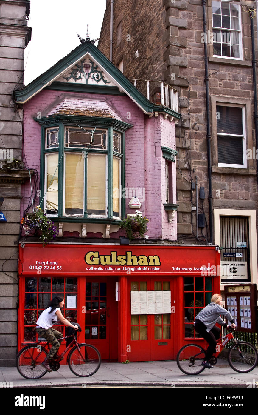 Two female cyclists riding past a the Gulshan Indian restaurant along the Nethergate in Dundee, UK Stock Photo