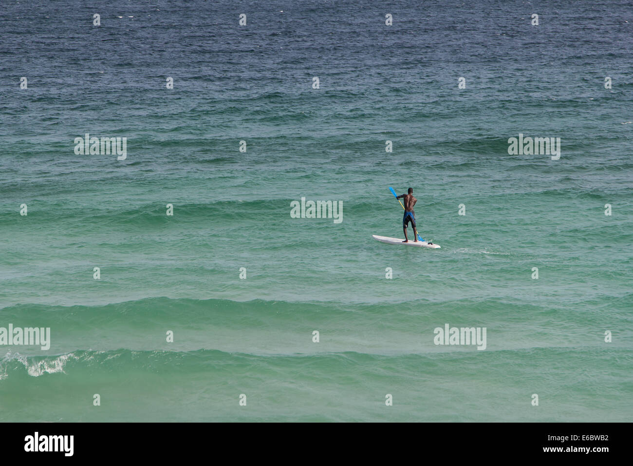 Barbados man paddle boarding on turquoise blue sea in the Caribbean. Stock Photo