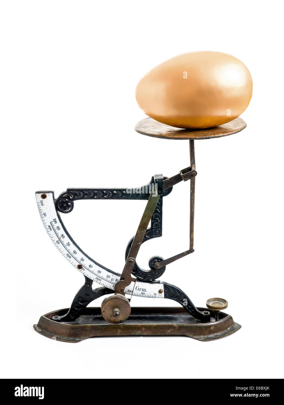 Giant golden egg on old scales shot on white Stock Photo